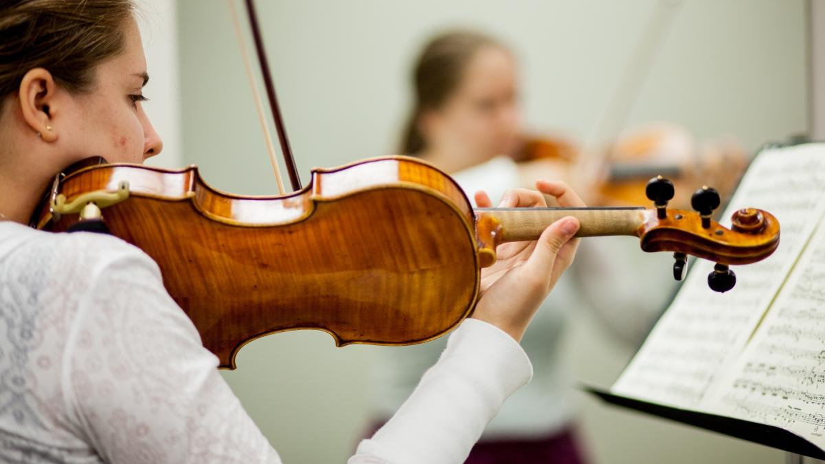 Young woman reads sheet music while playing the violin